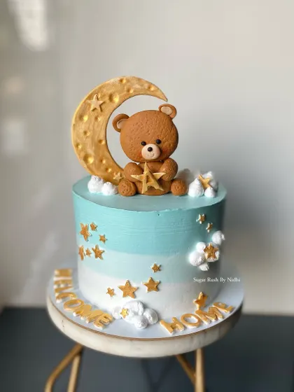 A sweet "Welcome Home" cake for a newborn baby. This cake features a teddy bear sitting on a crescent moon, surrounded by stars.