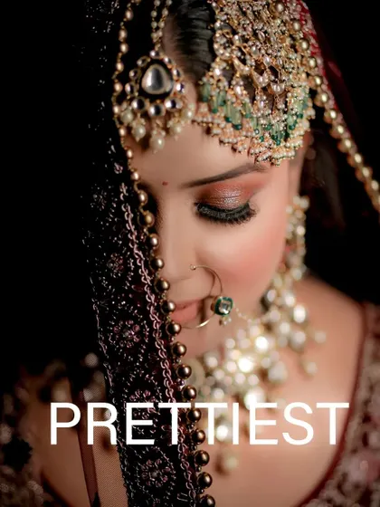 A close-up shot of a bride's face, partially covered by her beaded dupatta, highlighting her beautiful eye makeup.