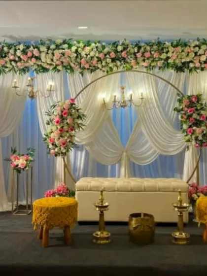This elegant engagement setup features a gold ring backdrop, white drapes, and traditional brass lamps, blending modern and classic elements.