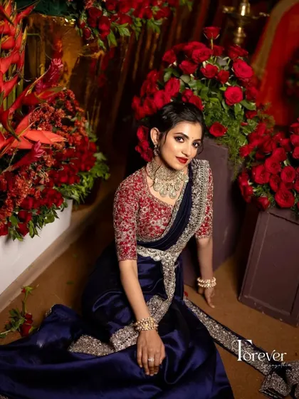 A beautiful, candid moment of the bride in her reception attire, surrounded by flowers. The makeup is classic and elegant, with a bold red lip.