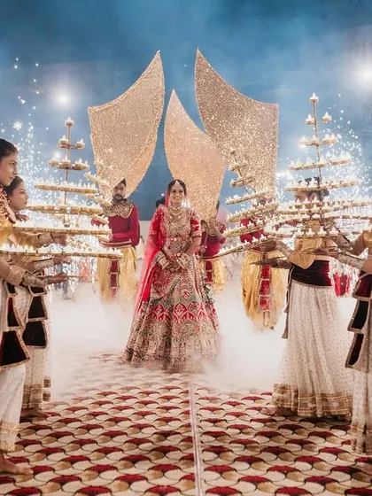 A truly grand bridal entry, with the bride walking through a path of cold pyros and smoke, flanked by dancers holding multi-tiered lamps.