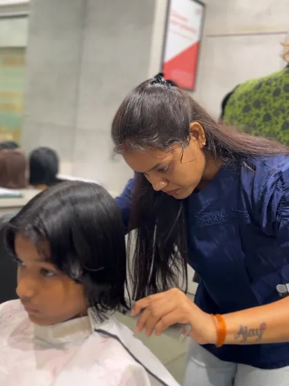 A student focuses on the details of a haircut, learning the precision required to become a professional hairstylist.