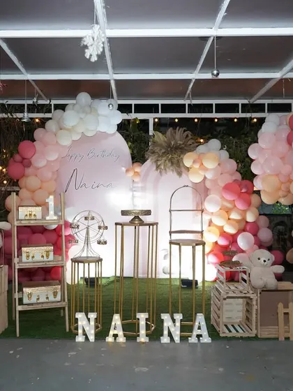A classic teddy bear themed birthday party. The setup includes a balloon arch in rustic colors, multiple teddy bears, and a personalized name sign in marquee letters.