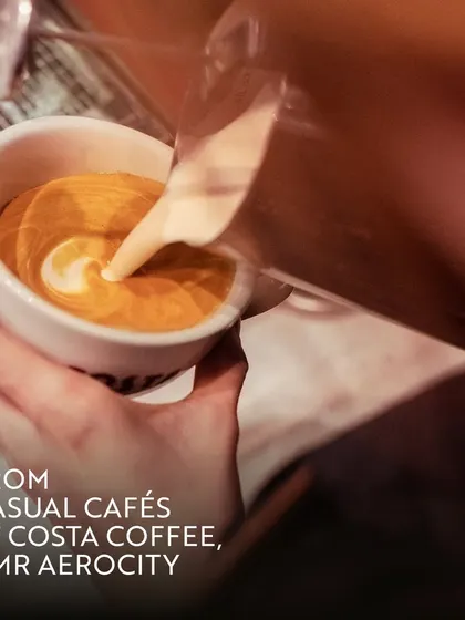 A barista pours intricate latte art at Costa Coffee. This close-up shot emphasizes the skill and care that goes into preparing each cup, enhancing your daily coffee ritual.