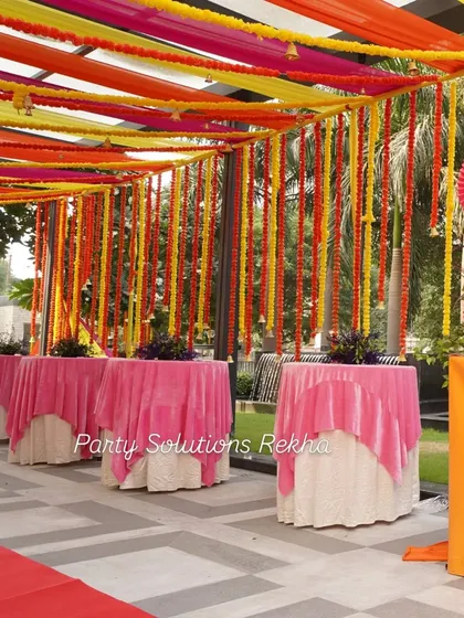 Another view of the colorful draped ceiling and marigold curtain, showing how it creates a cohesive and celebratory atmosphere throughout the entire venue. The pink table overlays tie the whole look together.
