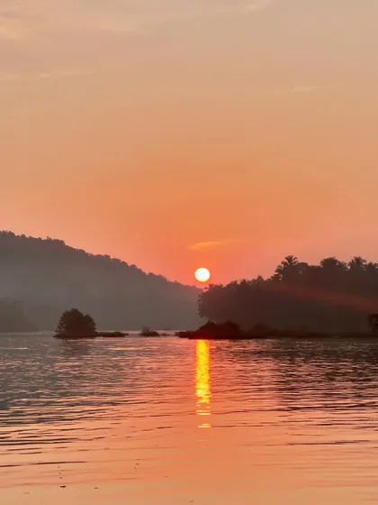 The sun setting over the calm backwaters, painting the sky and water in shades of orange.