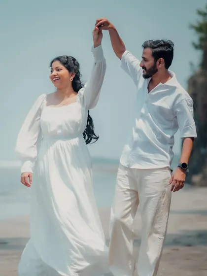 A joyful, spontaneous dance on the beach. This photo captures a moment of pure happiness and movement, with the bride's white dress flowing in the gentle sea breeze.