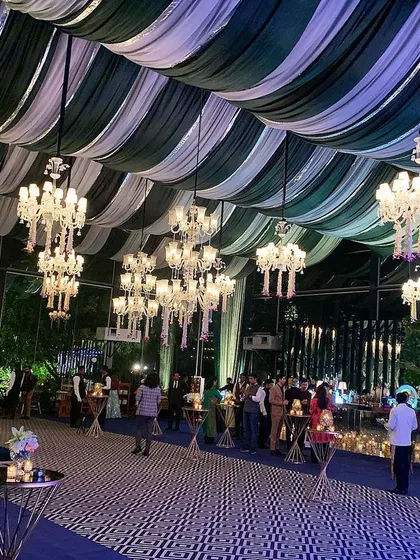 An elegant and sophisticated cocktail lounge defined by striking green and white striped ceiling drapes. The geometric-patterned floor and dozens of crystal chandeliers add layers of texture and luxury to the indoor space.