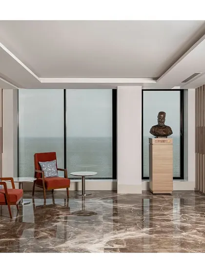 The visitor waiting lounge is designed without a traditional reception desk, instead using comfortable seating and a bust sculpture to create an elegant space with panoramic sea views.