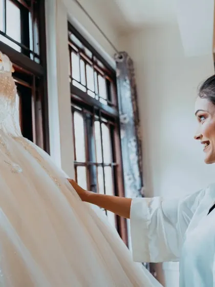 The bride admiring her wedding dress before putting it on, a moment of quiet anticipation.