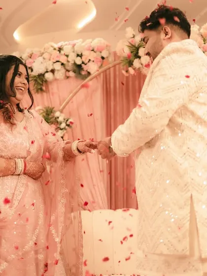A beautiful moment from an engagement ceremony, with the couple framed by a floral arch and falling petals.
