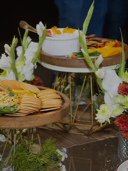 A beautiful display of tiered platters with fresh dips and crackers, adorned with flowers. This showcases how we integrate floral design directly into our food presentations.
