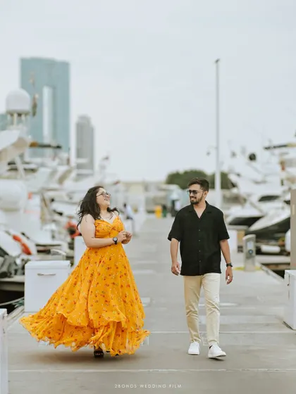 A joyful, candid shot of the couple walking along the pier, her laughter echoing the carefree spirit of their pre-wedding celebration in Dubai.