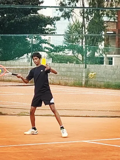 A junior competitor connects with the ball on a forehand shot during an AITA U-14 tournament match on the clay court.