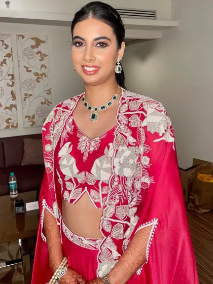 A vibrant reception look in a stunning red outfit with a modern cape.