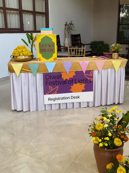 The registration desk for a "Diwali Festival of Lights" party. The table is decorated with a colorful banner and a bowl of marigolds, creating a warm and welcoming first impression.