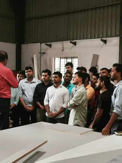 A group of students observes a presentation in a factory setting, bridging the gap between classroom theory and real-world production.