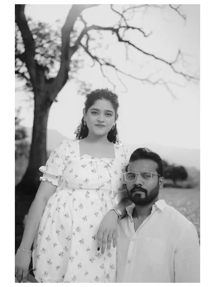 A classic black and white portrait of a couple in a field. Their direct gaze at the camera gives the photo a strong, confident, and timeless quality.