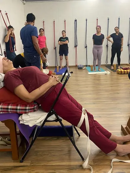 A student in a therapeutic setup for varicose veins and tired legs. The legs are elevated and supported by a bench, chair, and belts to improve circulation.