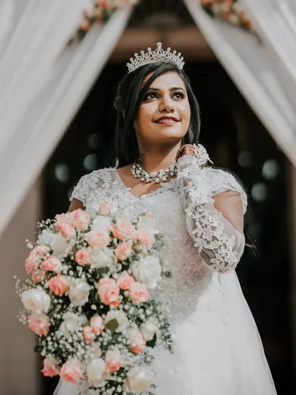 The bride, holding her bouquet, looks up with a radiant expression, perfectly capturing the magic of her wedding day.