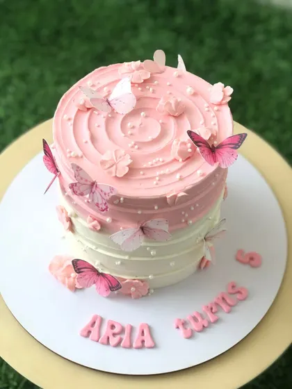 A pink ombre cake with a swirl top, decorated with delicate pink butterflies.