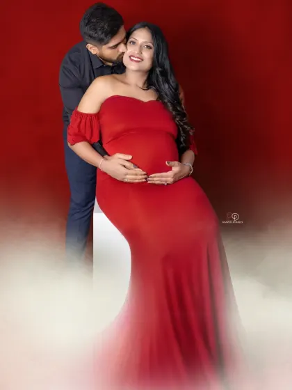 A classic red-themed couple's portrait filled with love and anticipation. The dad-to-be’s gentle kiss and the mom-to-be’s happy smile make this a perfect shot.