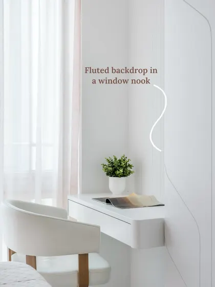 A minimalist desk set beside a tall, light-filled window gets a quiet boost of texture from its vertical fluted wall finish, creating a calm and contemporary thinking spot.