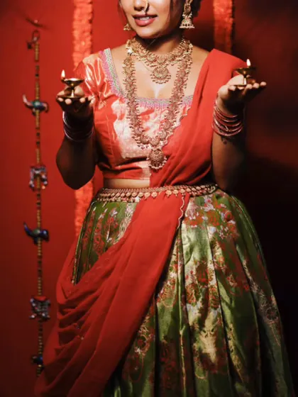 Holding diyas, this client embodies the spirit of celebration in this beautiful green and red half saree.