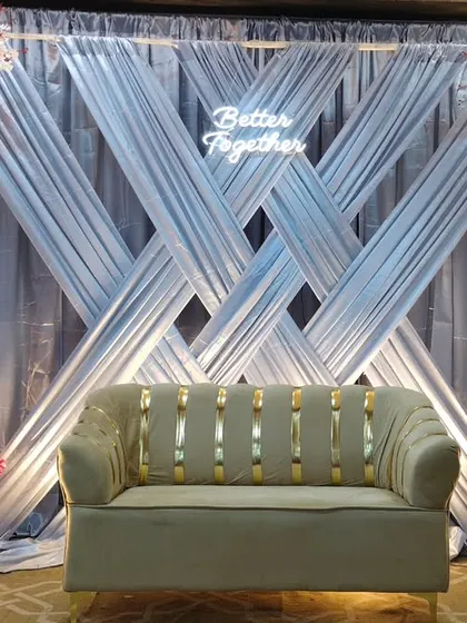 A modern engagement backdrop with crisscross silver drapes and arches of red and white flowers. The "Better Together" neon sign adds a trendy, personal touch to the stage.
