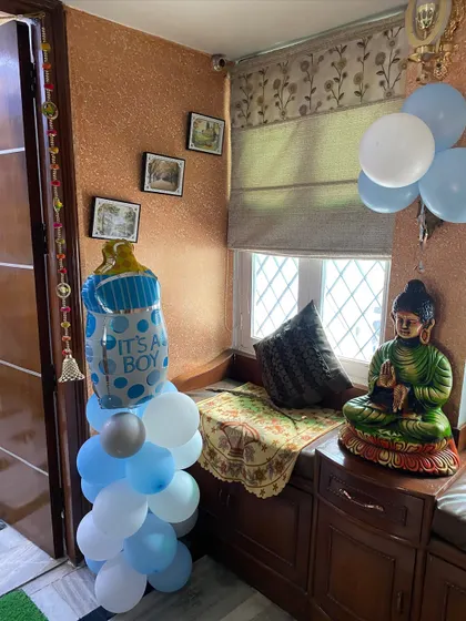 A baby bottle foil balloon on a pillar of blue and white balloons, placed in a cozy corner of the house.
