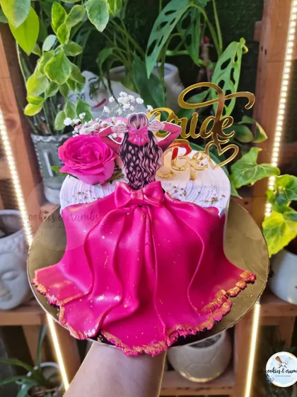 An adorable and glamorous cake for a bride-to-be. This design features a fondant doll in a vibrant pink dress, complete with a "Bride to Be" topper and fresh flowers.