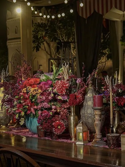 The bar area, decorated with a long runner of lush, jewel-toned flowers and brass decor. We ensure that every part of the event, including functional spaces, is beautifully integrated into the overall theme.