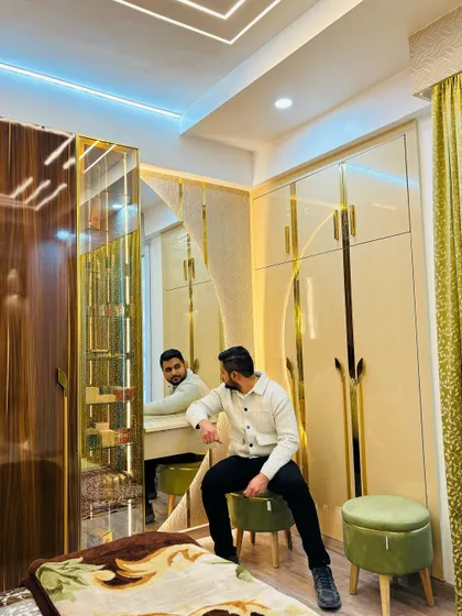 A luxurious master bedroom with gold accents. This room features a stunning wardrobe with gold-profile handles, a matching dressing table, and a full-length mirror, creating a glamorous and elegant space.