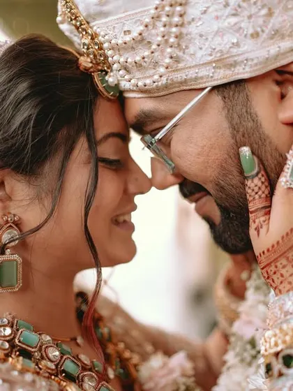 An intimate portrait of the couple, their foreheads touching, eyes closed in a moment of pure connection.
