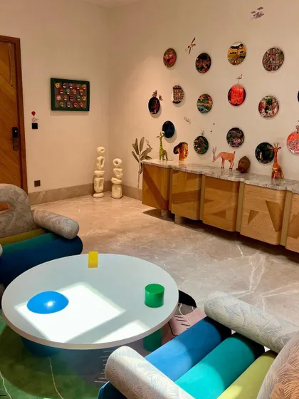 The same playful armchair shown in its environment, next to a custom coffee table and a unique wall art installation. This view shows how our pieces contribute to a cohesive, maximalist interior.