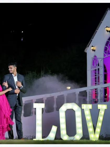 A dramatic night-time pre-wedding photo in front of our chapel, using the 'LOVE' prop and a flowing gown to create a stunning visual.