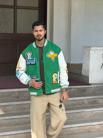 A cool, confident pose in a green and white varsity jacket. This showcases my ability to model trendy streetwear.