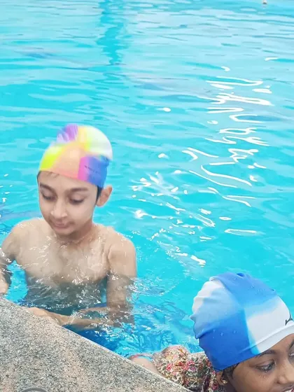 A close-up of two children in the pool, wearing their colorful swim caps and ready to learn.