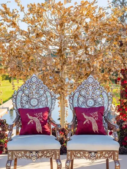 Ornate silver chairs with custom embroidered cushions, set against a golden tree mandap for the Hindu wedding in Marrakech.