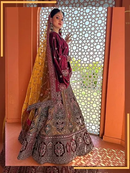 The rich colors and detailed embroidery of this bridal lehenga are captured perfectly in this shot by the window.