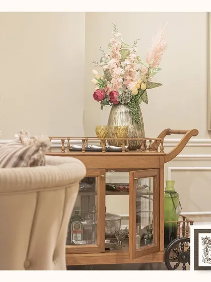 This wooden bar trolley features glass-paneled cabinet storage, providing a beautiful way to organize and display your barware. Its top surface is perfect for serving or holding a decorative floral arrangement.