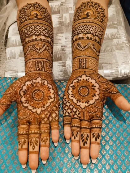 Mandala art is always in trend for its beauty and symmetry. This bridal design features a prominent mandala on the palm, with peacock and geometric patterns extending up the arm.