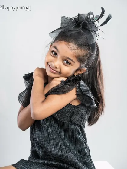 A girl in a black dress and fascinator, with a sweet and slightly shy expression. Her personality shines through in this simple portrait.