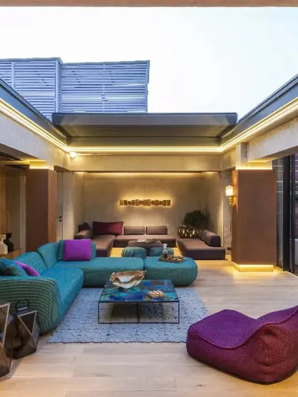 This vibrant lounge in a New Delhi residence is an entertainment area designed for soulful moments. We used eclectic Paola Lenti furniture against concrete and rust-finished walls, with a retractable roof for a seamless connection to the outdoors.