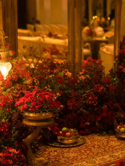 The warm, ambient lighting from antique lamps and candles created a soft glow on the red floral arrangements and patterned carpets, making the large ballroom feel intimate and romantic.
