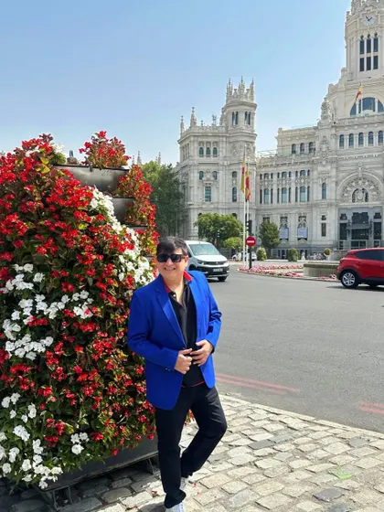 Posing next to a vibrant floral arrangement in Madrid, adding another layer of color to the scene.