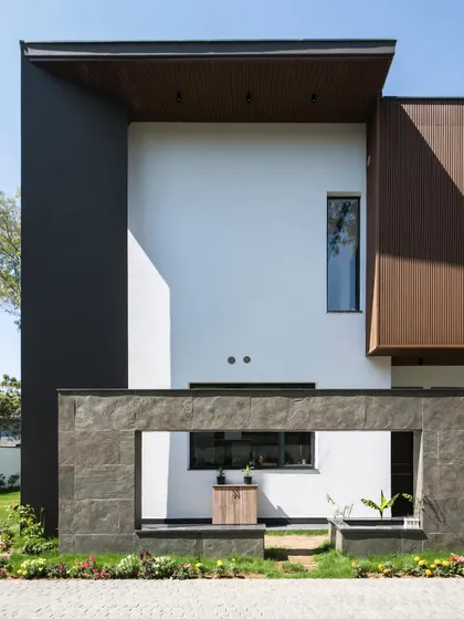 A detail of the Triveni Farmhouse facade shows a framed opening in a stone-clad wall, offering a peek at the space behind. This technique of creating layered views and playing with solid and void is a signature of our contemporary design approach.
