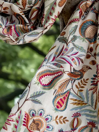 A detailed shot of our Ethereal Elegance fabric, showcasing the handcrafted embroidery of a graceful bird amidst vibrant florals, woven from premium natural fibers.