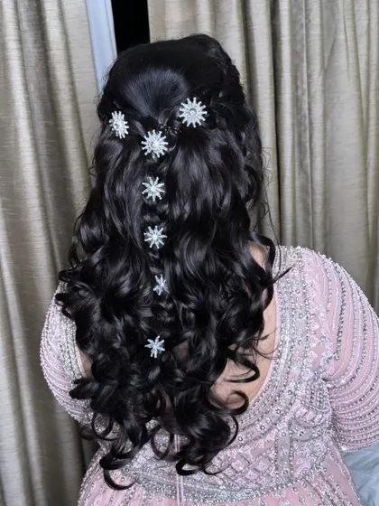 Stars in her hair. This beautiful open-curl hairstyle is decorated with star-shaped clips, adding a touch of whimsy and sparkle for a sangeet or reception.