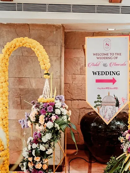 A personalized welcome signage for wedding guests at Fariyas Resort. The sign is elegantly decorated with marigold arches and floral bouquets, providing clear directions with a decorative touch.